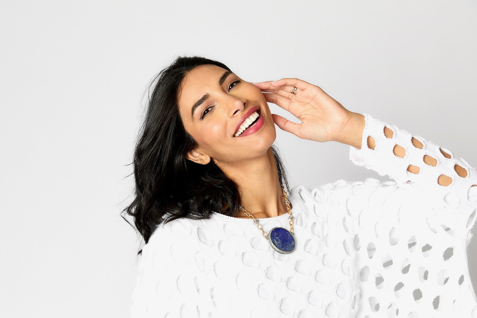 Woman wearing a white statement top and lapis necklace