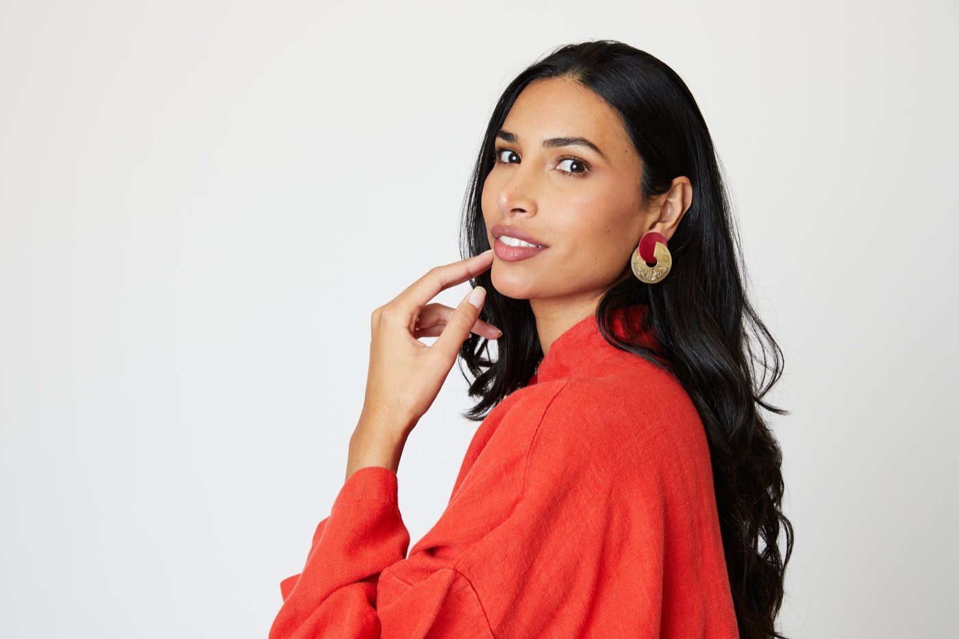 Woman wearing statement jewelry and a red natural-fabric top