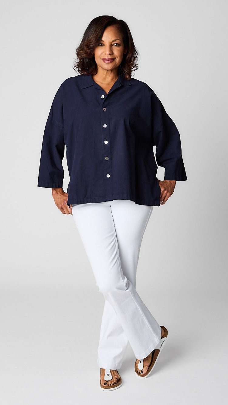 Model wearing indigo boxy button up, white bootcut denim jeans, and white sandals.