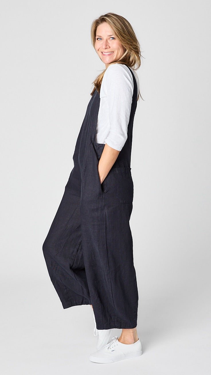 Model wearing "ink" linen overall jumpsuit with wide cropped dart leg, white 3/4 sleeve bias cut tee, and white sneakers.