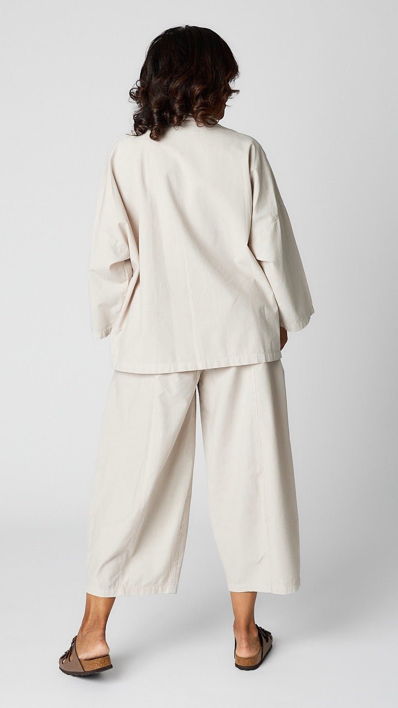 Model wearing cloud button-up top with relaxed hemline and 3/4 sleeves over cloud cropped one pocket pants and brown sandals.
