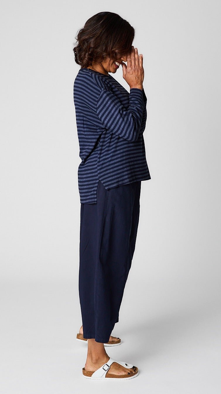 Model wearing "indigo" striped relaxed long sleeve tee, "indigo" cropped pant with one pocket, and white leather sandals.