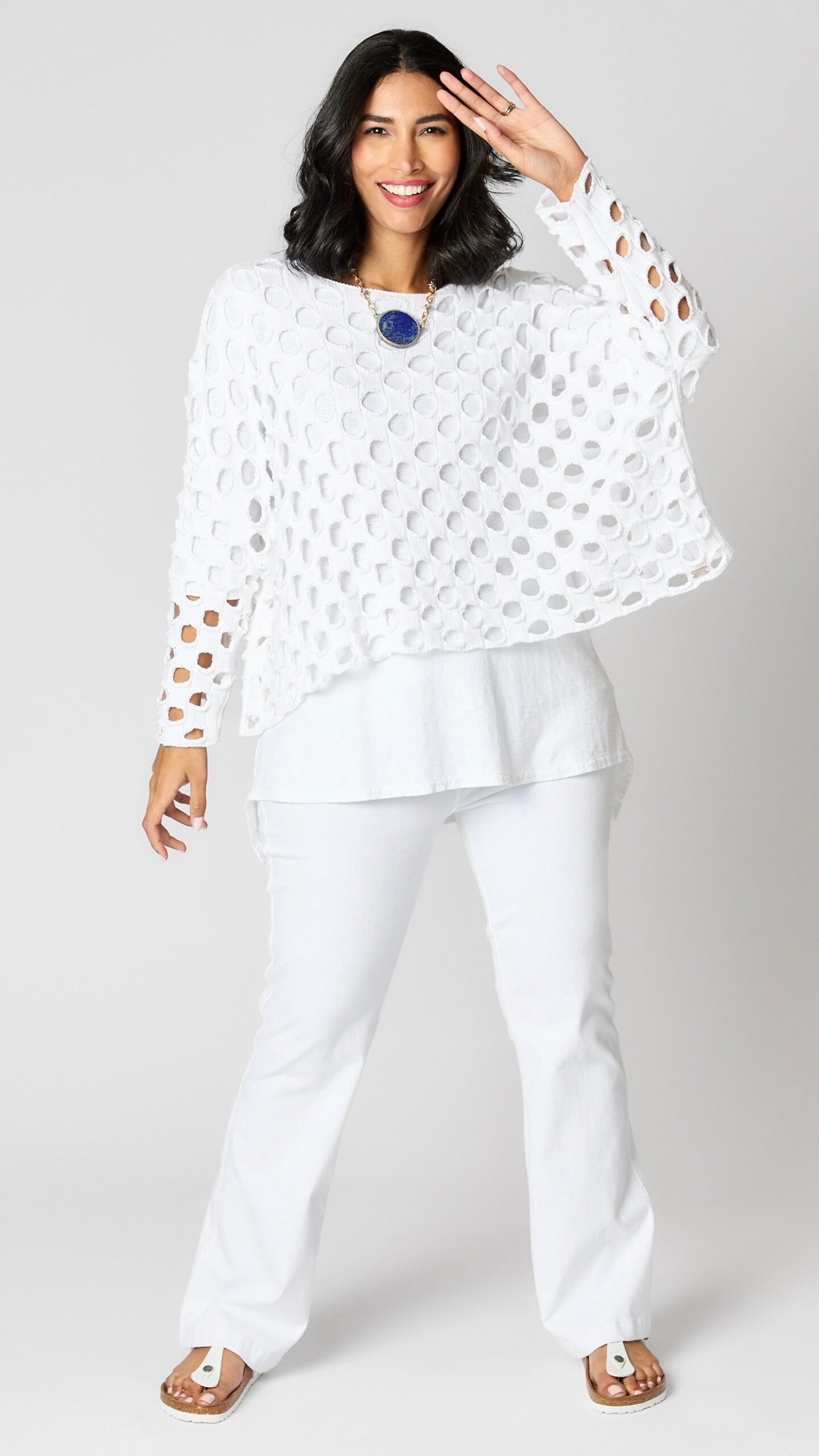 Model wearing white cotton handknit sweater overlay, white cotton-linen blend tunic, and white bootcut jeans.