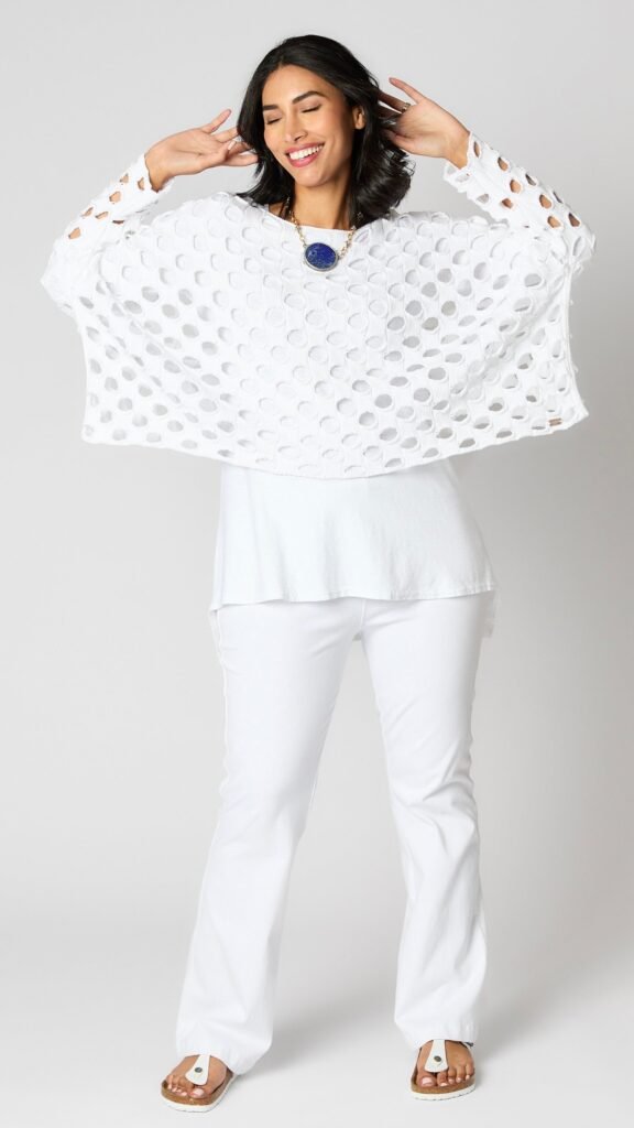 Model wearing white cotton handknit sweater overlay, white cotton-linen blend tunic, and white bootcut jeans.