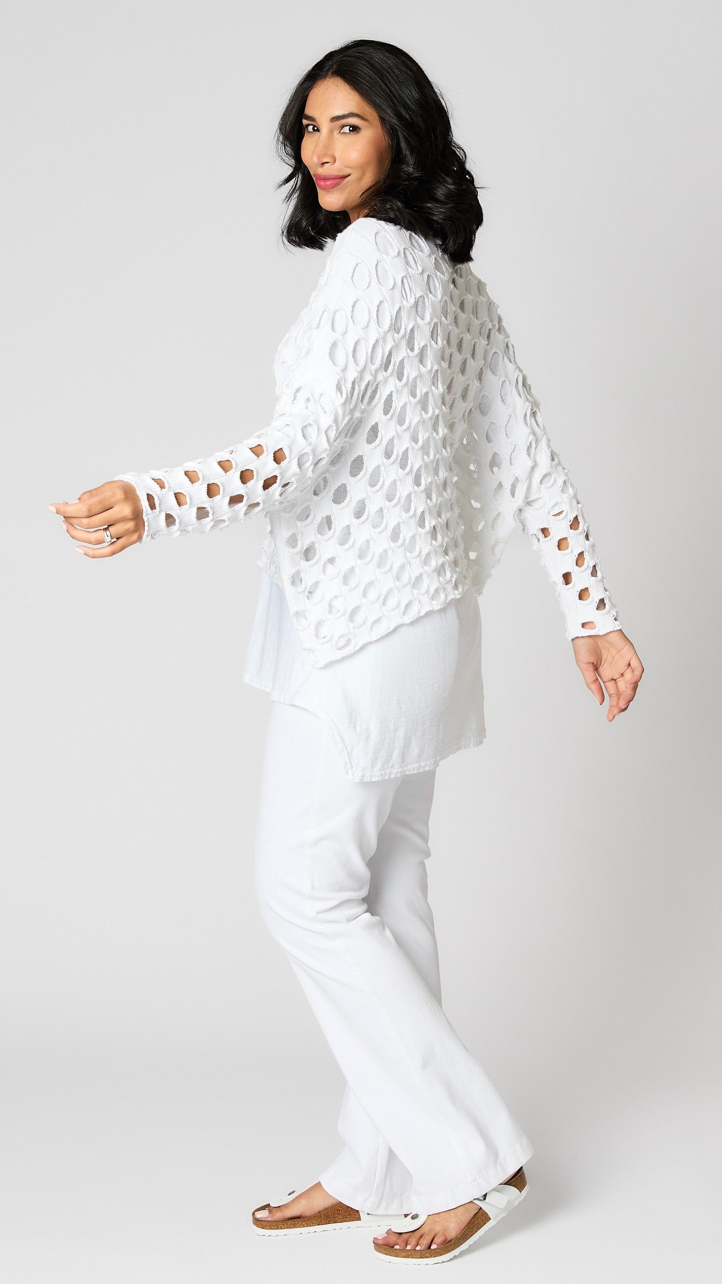 Model wearing white cotton handknit sweater overlay, white cotton-linen blend tunic, and white bootcut jeans.