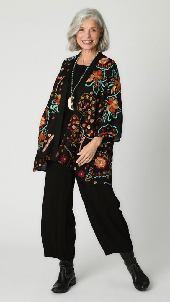 Model wearing black cotton kimono style jacket with turquoise and orange embroidery, black cropped top and black cropped dart pant in rayon with black leather boots.