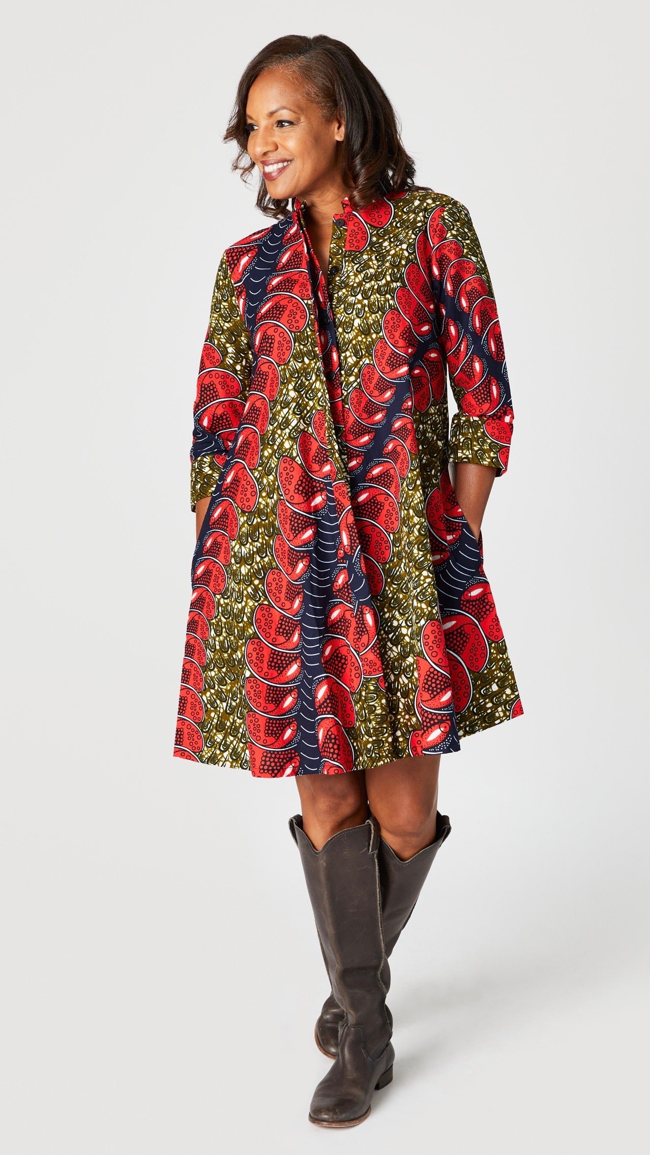 Model wearing "Red Herring" print Zuri dress with tall brown leather boots.